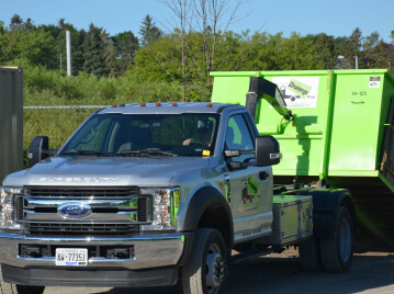 A junk hauling franchise disposal truck parked outdoors on a sunny day.